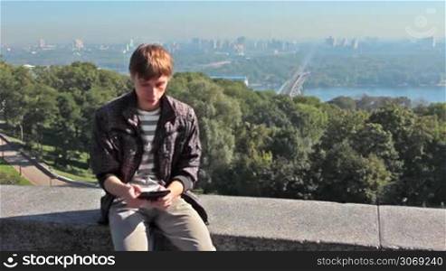 young man reading on electronic book, behind him very nice view of capital city, Kiev Ukraine