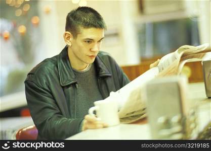 Young Man Reading the Newspaper at a Diner