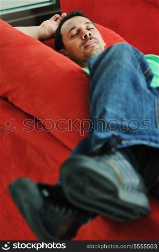 young man relax on red sofa and work on laptop at home indoor