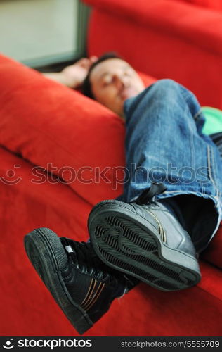 young man relax on red sofa and work on laptop at home indoor