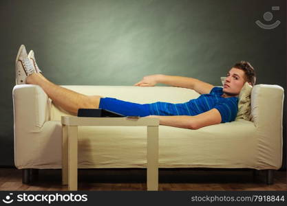 Young man relaxing on couch, tablet and mobile phone laying on table