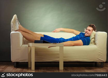 Young man relaxing on couch, tablet and mobile phone laying on table