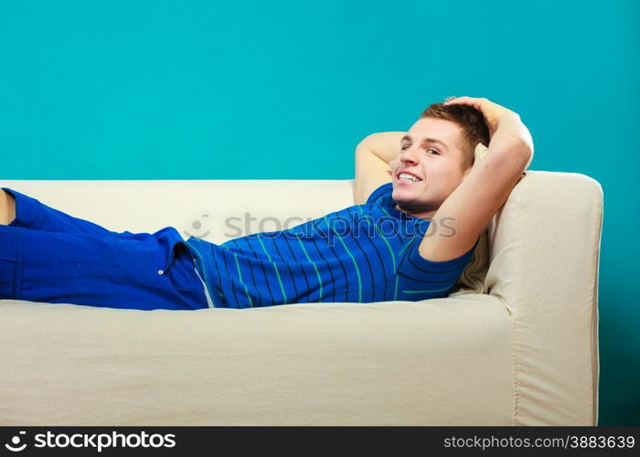 Young man relaxing on couch, teen positive boy laying lazy on bed blue background