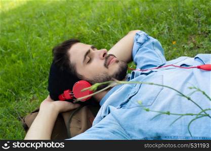 Young man relaxing on green grass with headphones. Leisure concept.