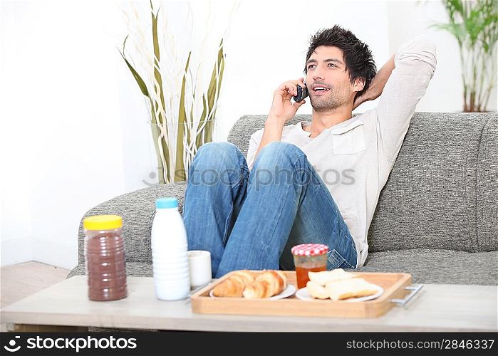young man relaxing on the couch and talking on the phone