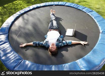 Young Man Relaxing On Trampoline With Laptop