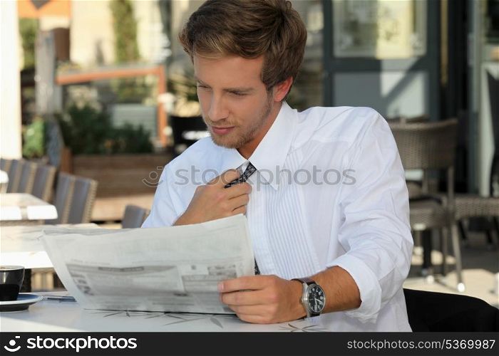 Young man relaxing reading newspaper