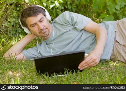 young man relaxing with a tablet and headphones, outdoor