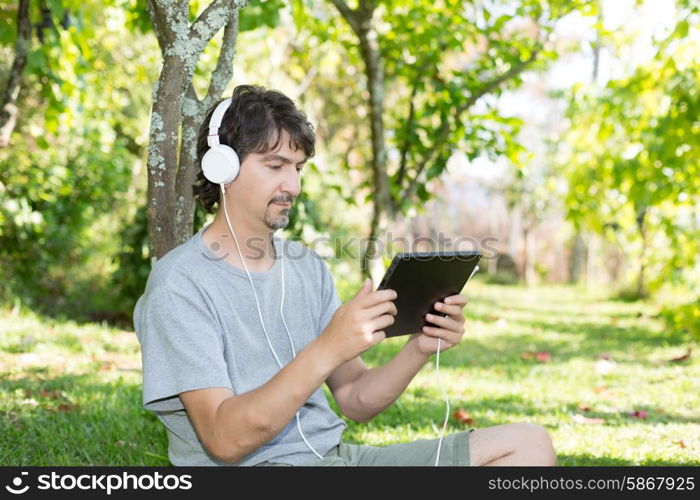 Young man relaxing with a tablet computer at a garden