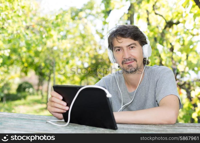 Young man relaxing with a tablet computer at a garden