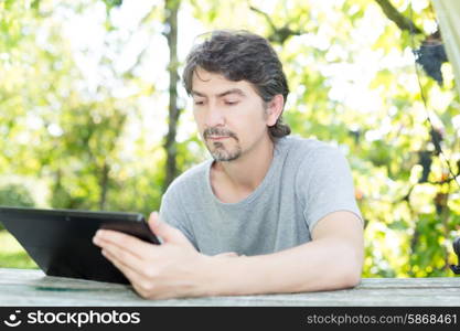 Young man relaxing with a tablet computer at a garden