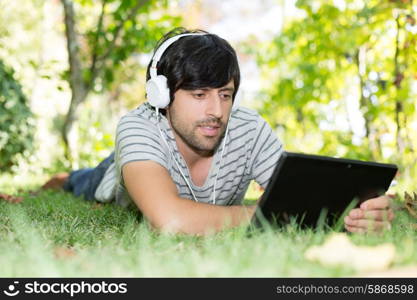 Young man relaxing with a tablet computer at a garden