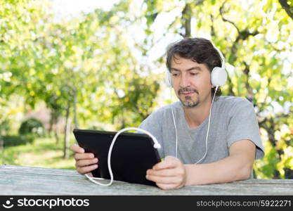 Young man relaxing with a tablet computer at a garden