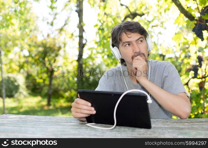 Young man relaxing with a tablet computer at a garden