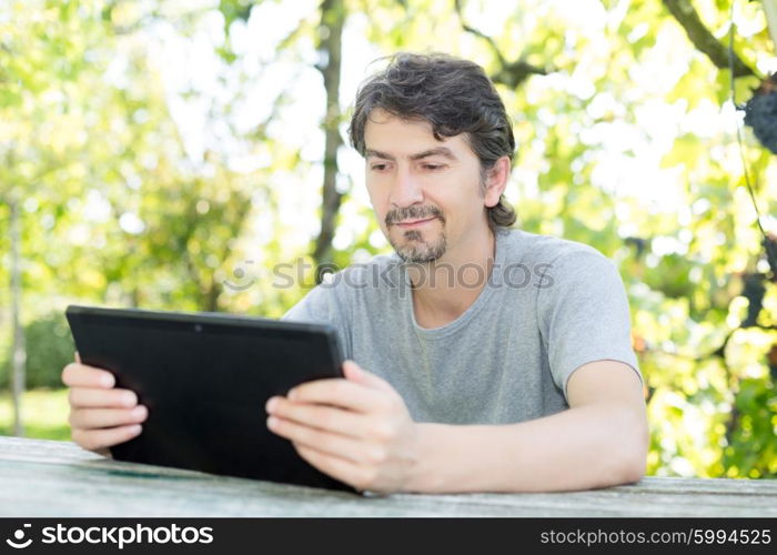 Young man relaxing with a tablet computer at a garden