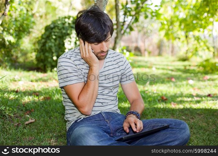 young man relaxing with a tablet pc and phone on a the park, outdoor