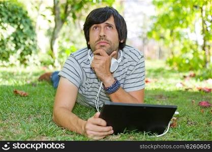 young man relaxing with a tablet pc listening music with headphones on a the park, outdoor