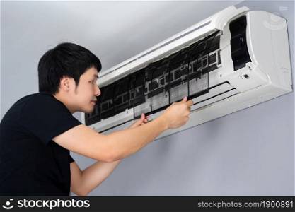 young man removing air filter of the air conditioner for cleaning at home