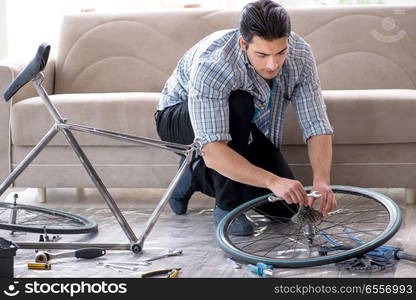 Young man repairing bicycle at home