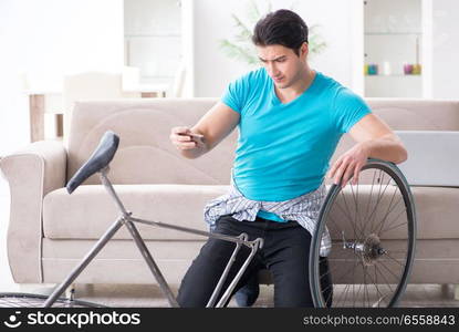 Young man repairing bicycle at home