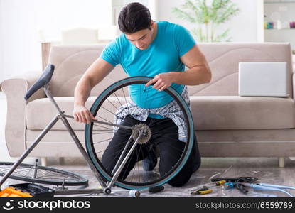 Young man repairing bicycle at home