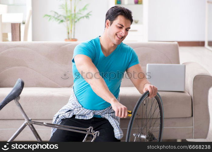 Young man repairing bicycle at home