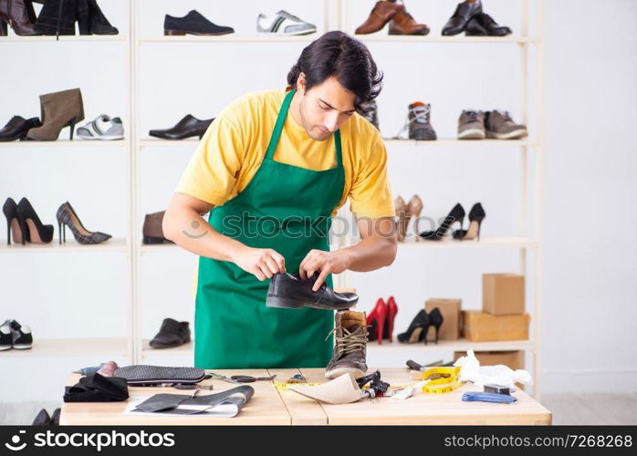 Young man repairing shoes in workshop 