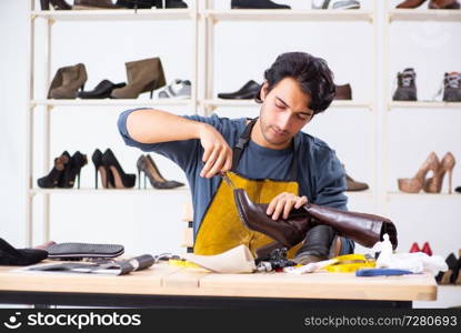 Young man repairing shoes in workshop 