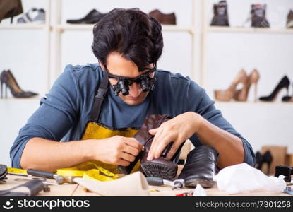 Young man repairing shoes in workshop 