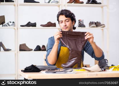 Young man repairing shoes in workshop 