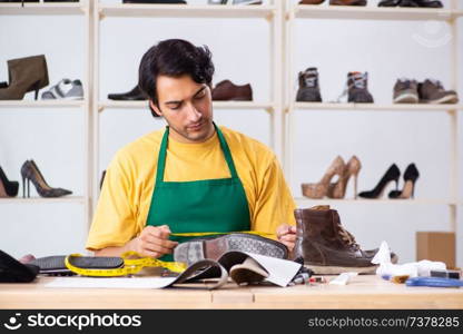 Young man repairing shoes in workshop 