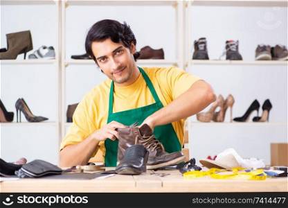 Young man repairing shoes in workshop 