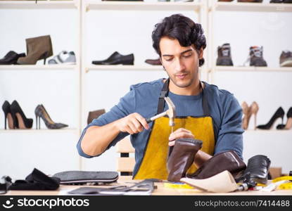 Young man repairing shoes in workshop 