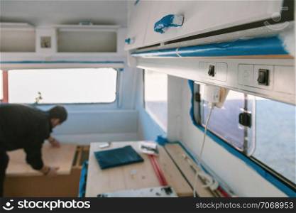 Young man restoring his old caravan from inside
