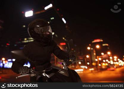 Young Man riding a motorcycle at night through the streets of Beijing