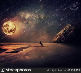 Young man riding a wild horse near the seaside in a starry night with a full moon and falling stars. New lands discovery, adventure and friendship concept.