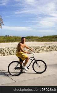 Young man riding bicycle on beach