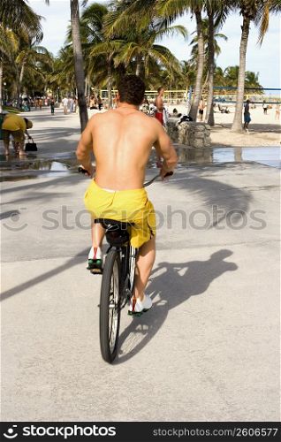 Young man riding bicycle on beach