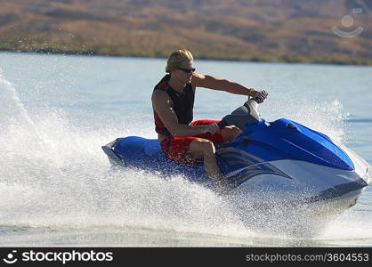 Young man riding jetski on lake
