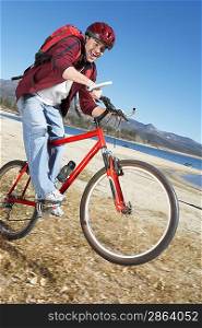 Young Man riding mountain bike on lake shore
