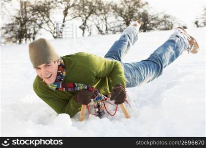 Young Man Riding On Sledge In Snowy Landscape