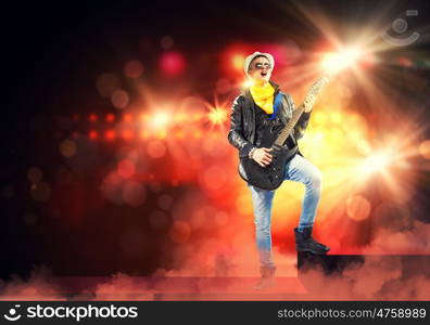 Young man, rock musician in jacket with guitar