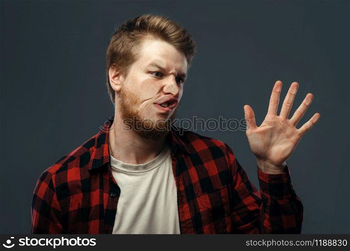 Young man&rsquo;s crazy face and a hand crushed on transparent glass. Male person with pressed grimace standing at the showcase, humor, uncomfortable looking, funny emotion. Man&rsquo;s crazy face crushed on transparent glass