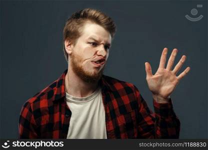 Young man&rsquo;s crazy face and a hand crushed on transparent glass. Male person with pressed grimace standing at the showcase, humor, uncomfortable looking, funny emotion. Man&rsquo;s crazy face crushed on transparent glass