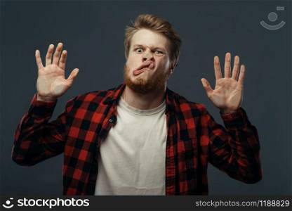 Young man&rsquo;s crazy face and hands crushed on transparent glass. Male person with pressed grimace standing at the showcase, humor, uncomfortable looking, funny emotion