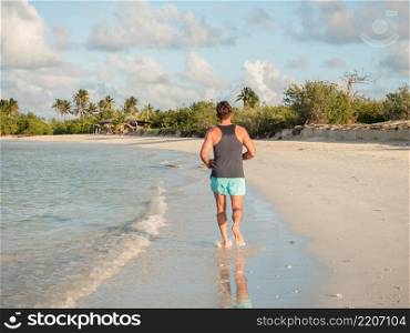 Young man running along the coast of the Atlantic Ocean. Close-up. Vacation and travel concept. Young man running along the coast of the Atlantic Ocean