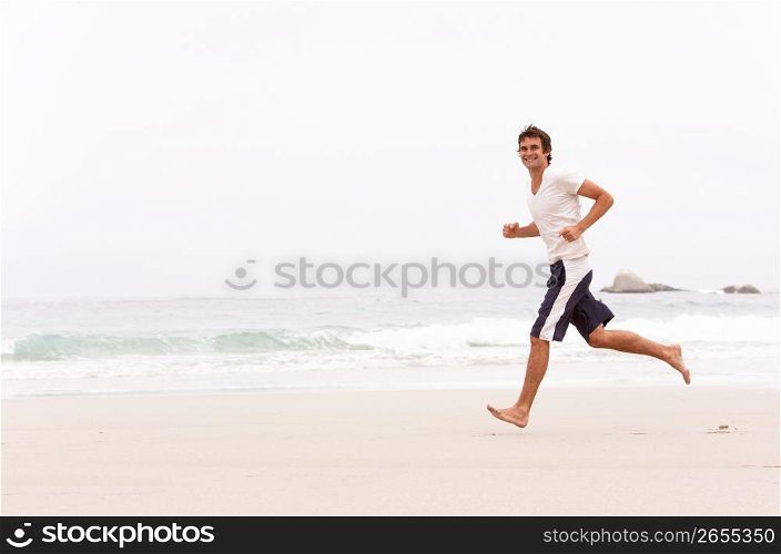 Young Man Running Along Winter Beach
