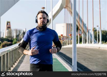 young man running and listening to music in an urban area