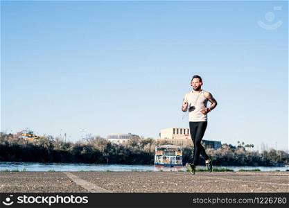 young man running around the harbor and listening to music with a pair of headphones