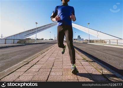 young man running down the street in front of a bridge